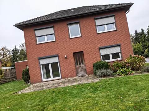 Handyfoto der hinteren Klinkerfassade mit Rollläden und Terrassentür