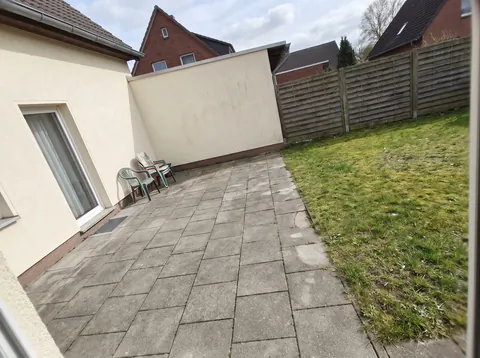 Handyfoto der gepflasterten Terrasse hinter dem Haus, die überdacht werden soll